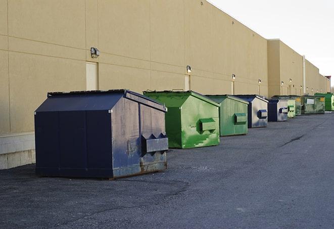 a compact construction dumpster being emptied by a waste disposal truck in Baker LA